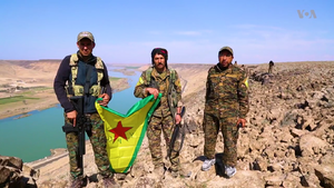 SDF Militants hold their flag outside the city of Raqqa