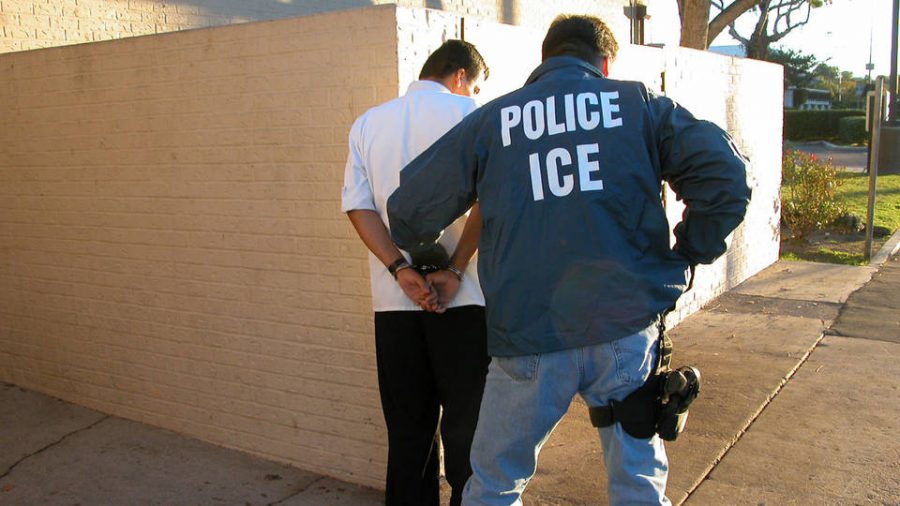 An ICE police officer arrests a man known to be an illegal immigrant outside his house in Pasadena, CA