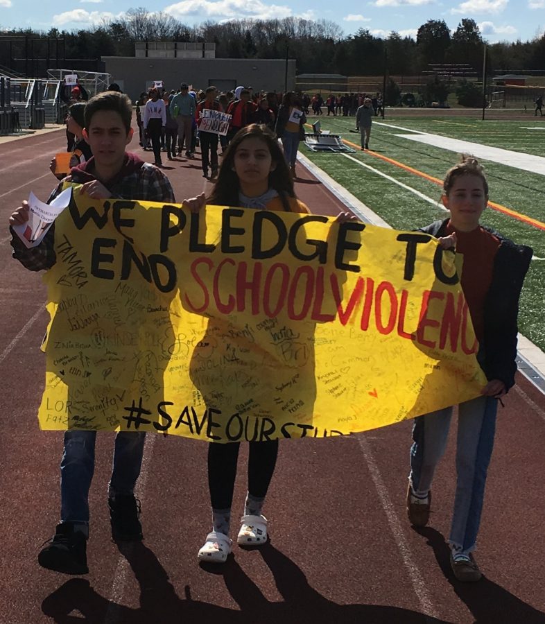 Ethan+Snider%2C+Rida+Dhanani%2C+and+Shelby+Green+carry+the+banner+leading+the+protest+against+school+violence.