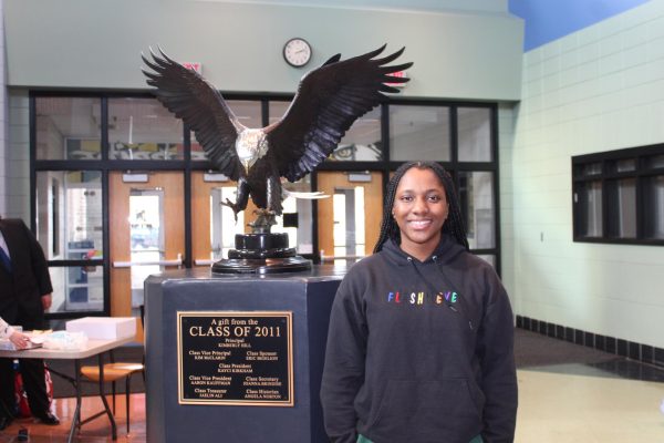 Kelechi smiles beside the eagle statue in the lobby.